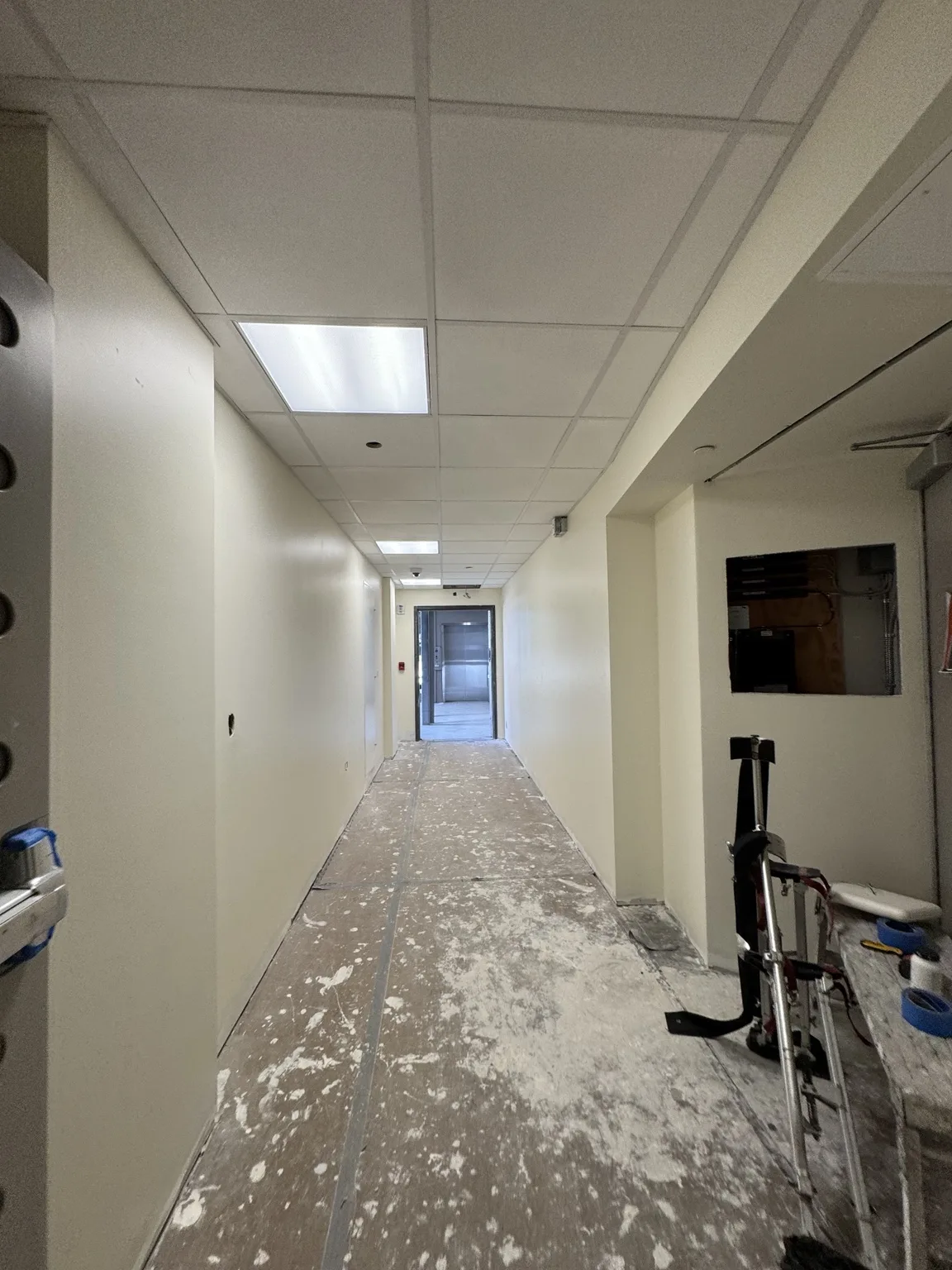 Long hallway with drywall walls and detailed ceiling
